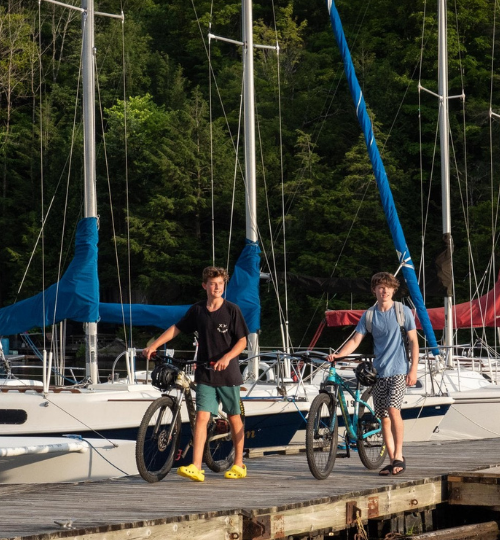 2 boys walking on a dock with their bikes
