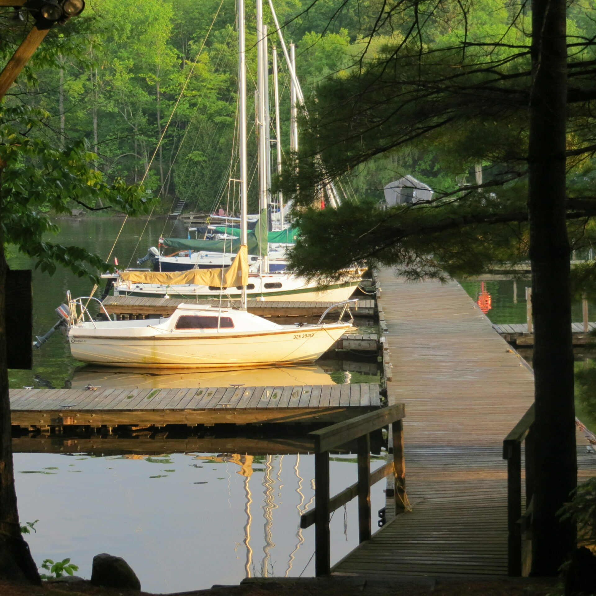 This is a photograph of a sandpiper sailboat along a dock at dusk